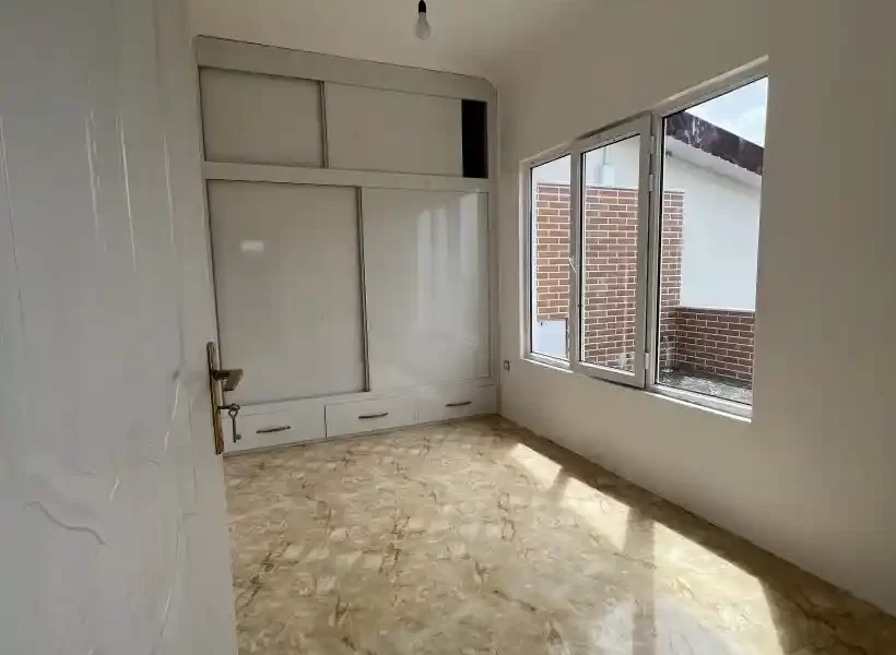 پمجره ی کوچک روبه تراس و کمد دیواری سفید اتاق خواب آپارتمان در بابل