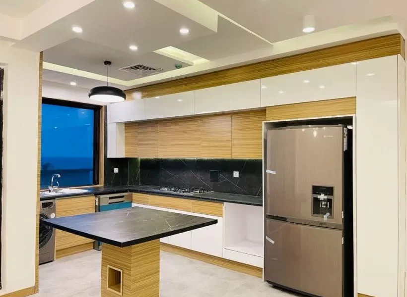 یخچال و کابینتهای قهوه ای رنگ و پنجره ور به محوطه آشپزخانه آپارتمان در بابلسر 54