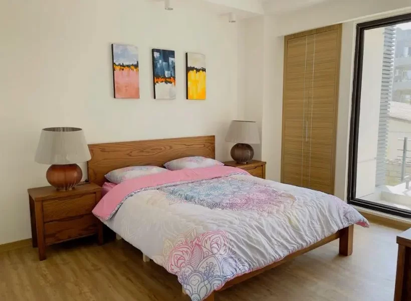 تخت خواب با روتختی سفید صورتی و میز غسلی چوبی در اتاق خواب آپارتمان در بابلسر 5253