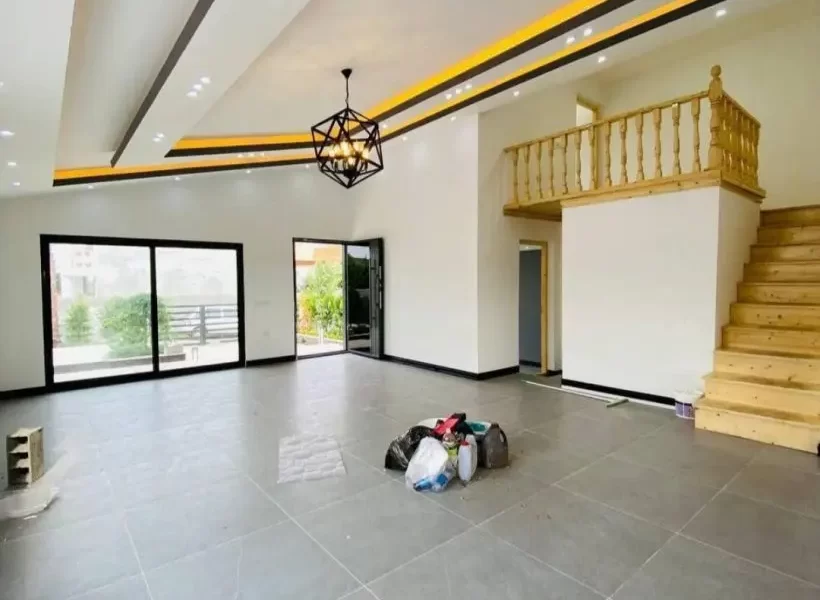 سرامیک طوسی رنگ و در رو به محوطه سرسبز و راه پله چوبی در سالن نشیمن ویلا در بابل