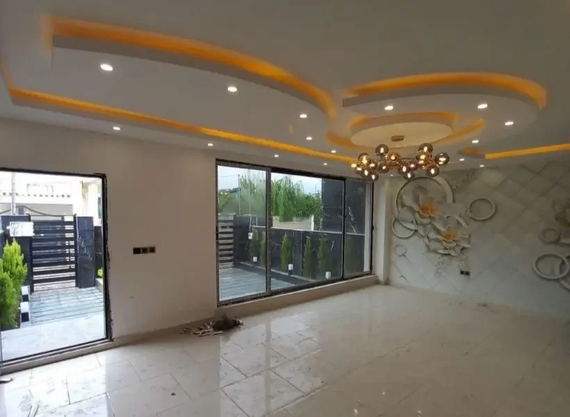 سرامیک سفید و درهای شیشه ای رو به محوطه سرسبز و سقف نورپردازی شده با نور زرد سالن نشیمن ویلا در زیرآب