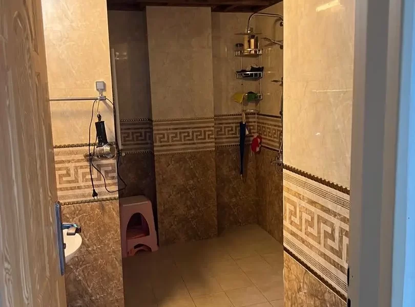 کاشی سفید کرمی و سشوار و صندلی صورتی در سرویس بهداشتی آپارتمان در زرگر