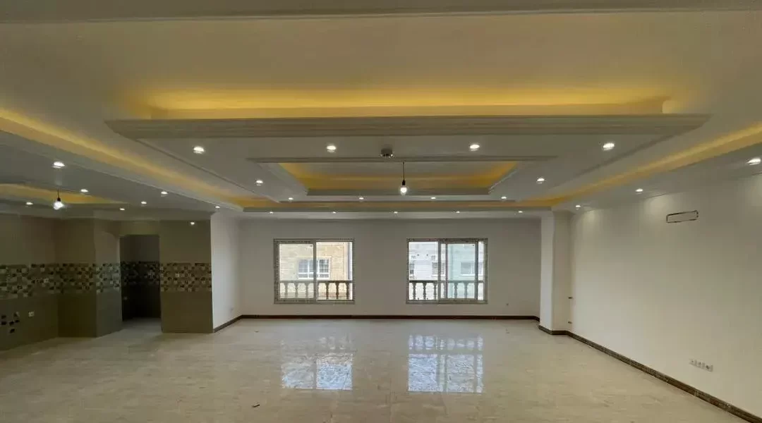 سرامیک کرمی و سقف نور پردازی شده با نور زرد سالن نشیمن آپارتمان در بهنمیر