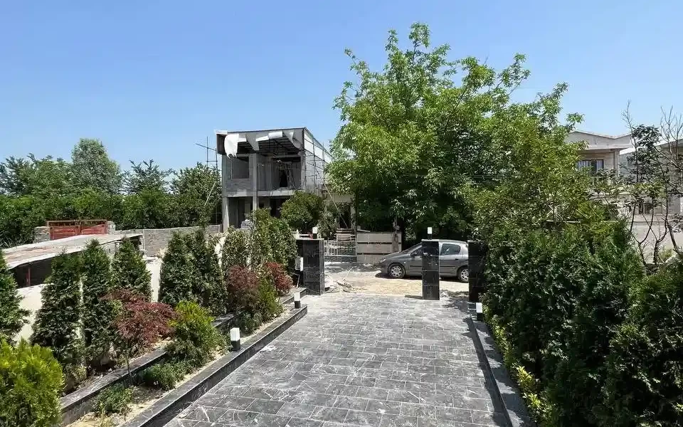 محوطه سنگ فرش شده و باغچه سرسبز ویلا در شیرگاه