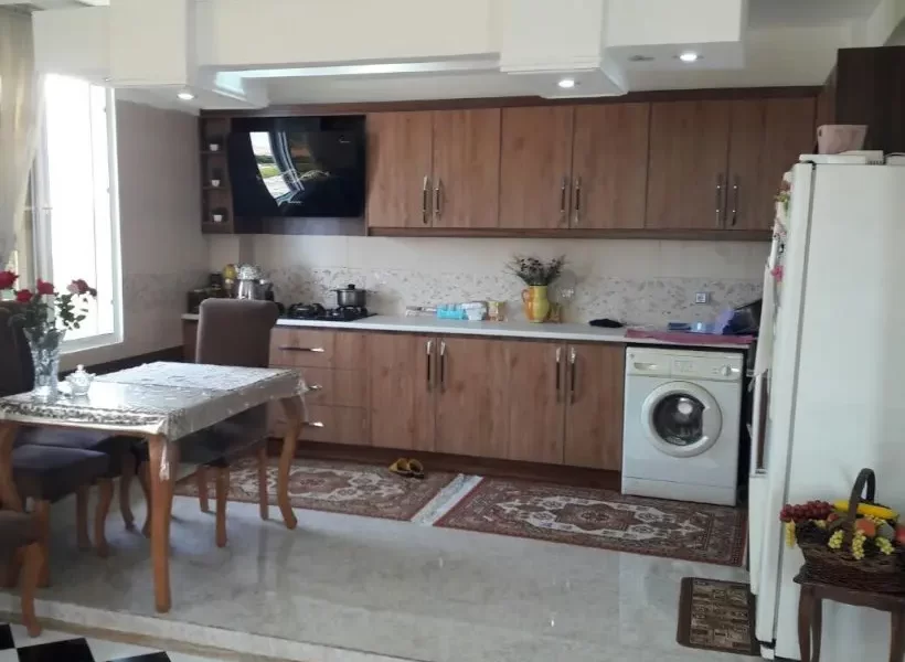 کابینت های چوبی و میز غذاخوری و لباسشویی و یخچال آشپزخانه آپارتمان در پل سفید