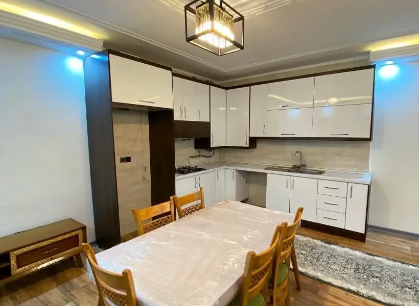 کابینت سفید و میز غذاخوری و سقف نور پردازی شده با نور زرد آشپزخانه ویلا در بابلسر