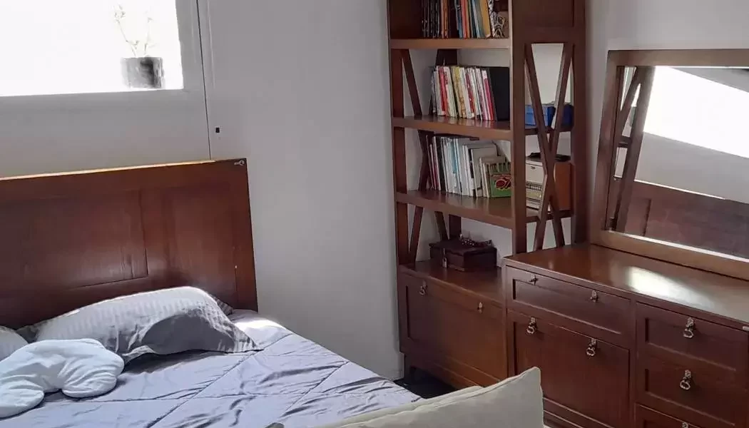 تخت چوبی با روتختی سفید و مبل و میز آرایش و کتابخونه اتاق خواب آپارتمان در پل سفید