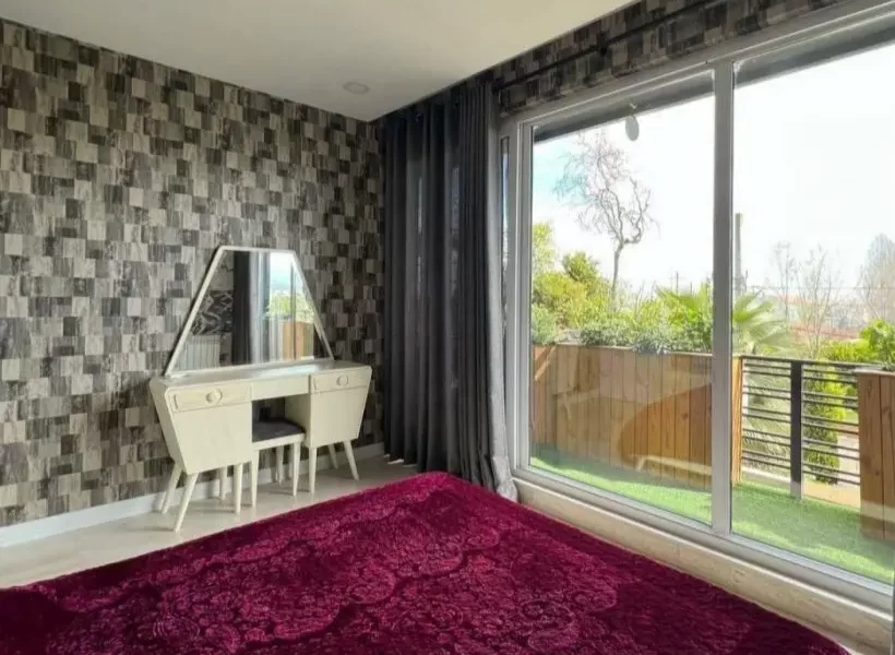 تخت خواب با روتختی بنفش و میز آرایش و درب رو به تراس اتاق خواب ویلا در بابل