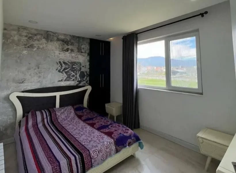 تخت خواب با روتختی رنگی و پنجره رو به محوطه سرسبز اتاق خواب ویلا در بابل