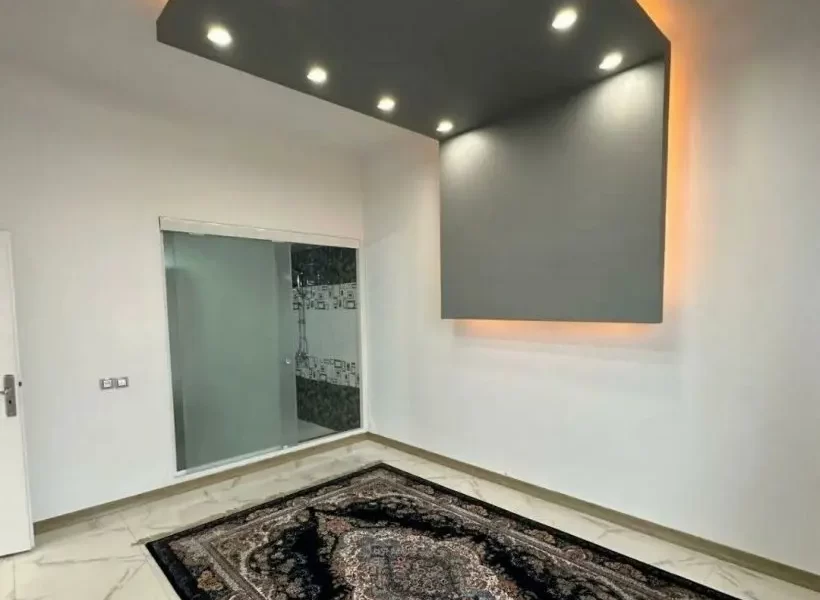 فرش سرمه ای رنگ و سرویس بهداشتی و سقف نور پردازی شده بانور سفید و نارنجی اتاق مستر ویلا در بابل