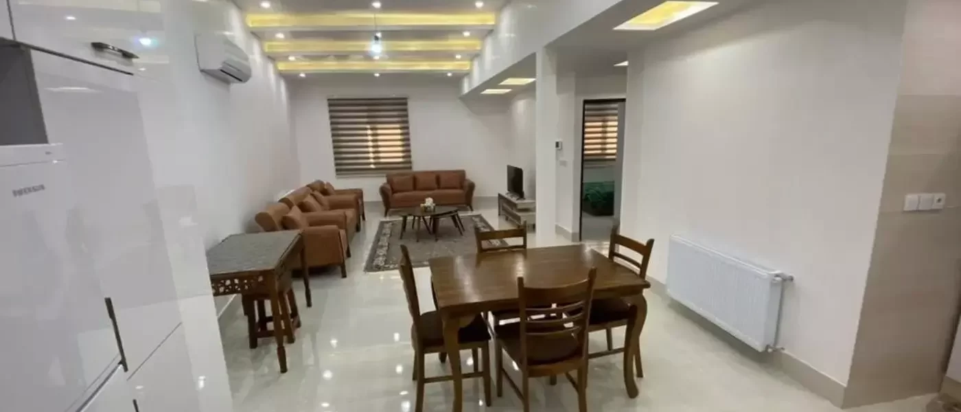 مبلمان قهوهای ومیز غذاخوری وسقف نور پردازی شده با نور زرد و سفید سالن نشیمن آپارتمان در قائم شهر