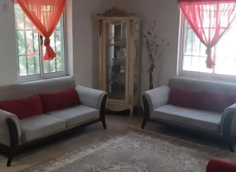 مبلمان سفید و پنجره رو به محوطه سرسبز سالن نشیمن خانه روستایی در باقرتنگه