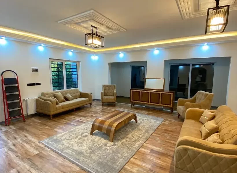 مبلمان قهوه ای رنگ و سقف نور پردازی شده با نور زرد سالن نشیمن ویلا در بابلسر