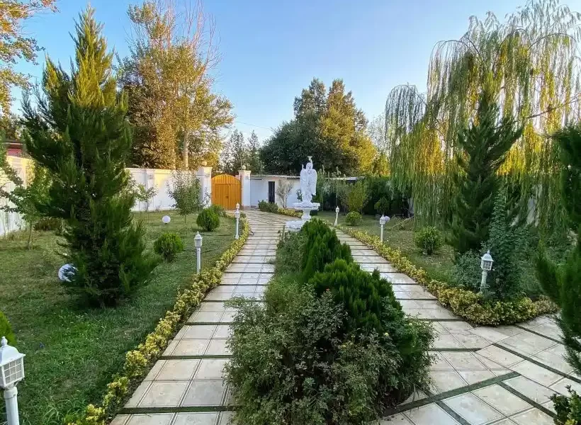 محوطه سنگ فرش شده و باغچه سرسبز و آب نما محوطه ویلا در بابلسر