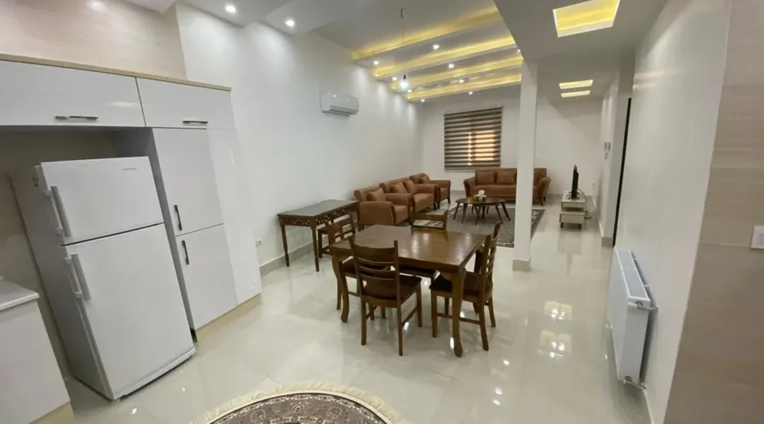 آشپزخانه با یخچال و کابینت های هایگلاس و اتاق پذیرایی آپارتمان در بابل 4156454