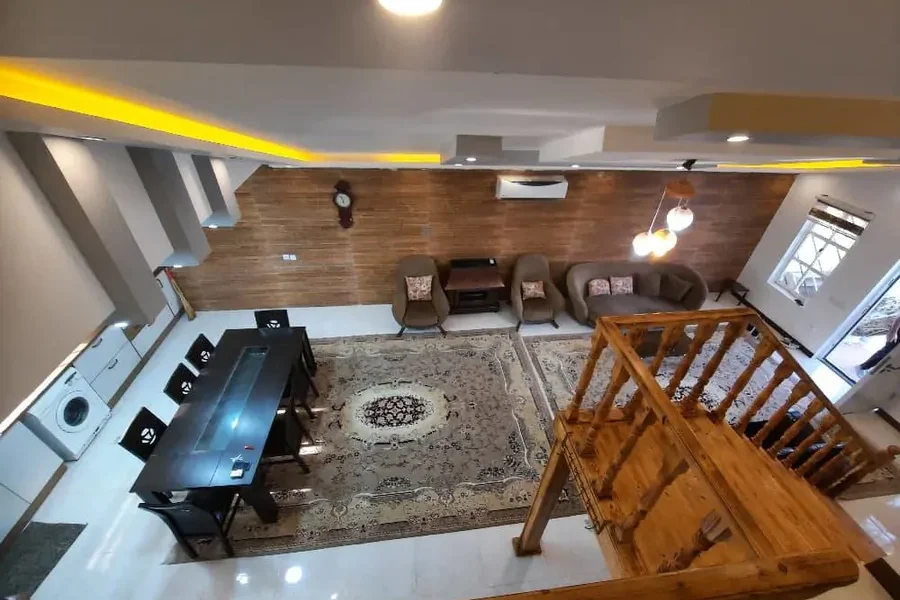 اتاق پذیرایی فرش شده با میز غاخوری و پله های همکف چوبی ویلا در بابلسر 415644