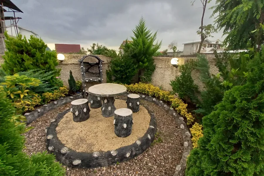 محوطه سازی سرسبز در کنار نیمکت و صندلی چوبی ویلا در بابلسر 15651